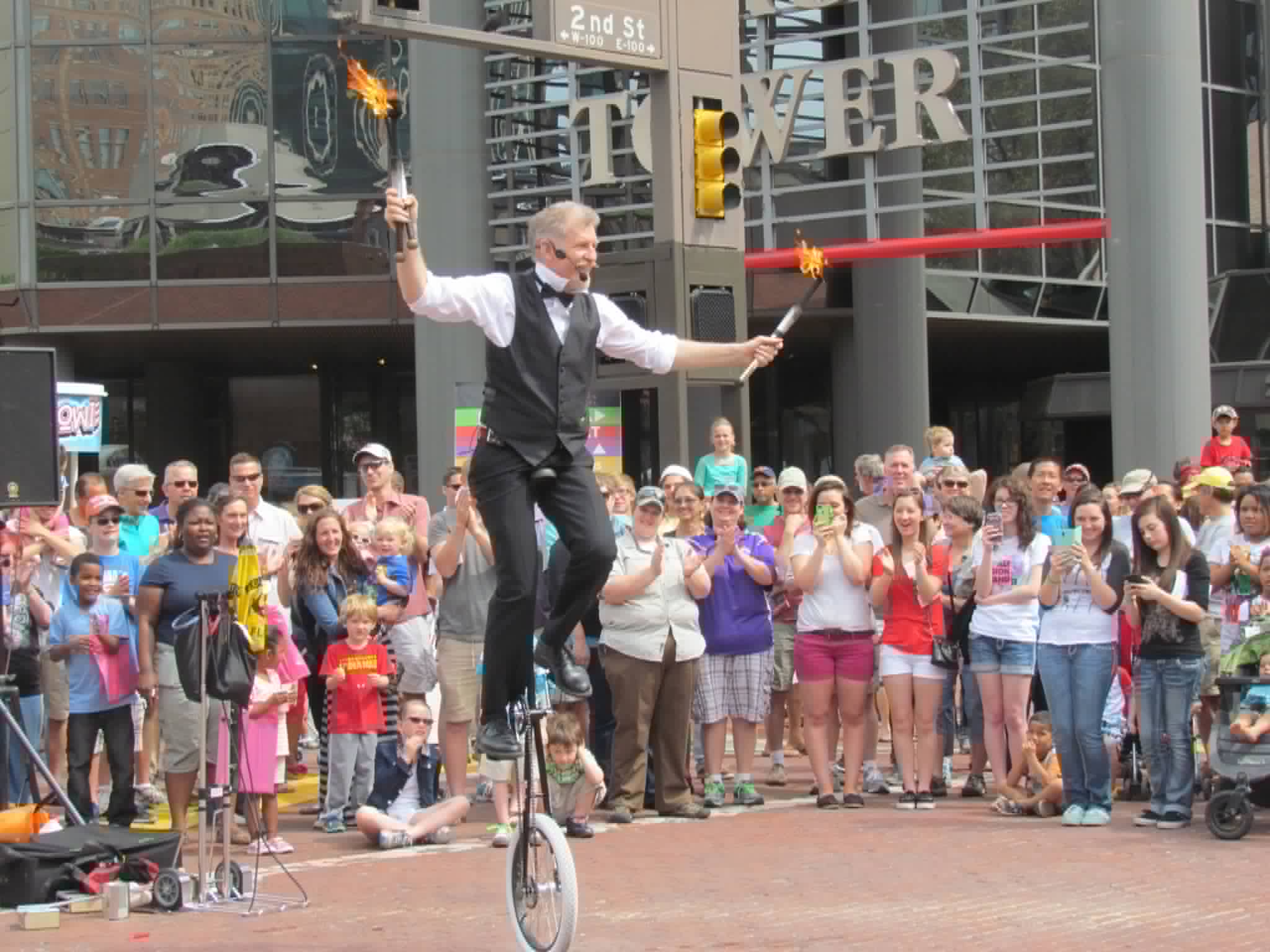 Fire torch juggling on a unicycle in front of a downtown crowd
