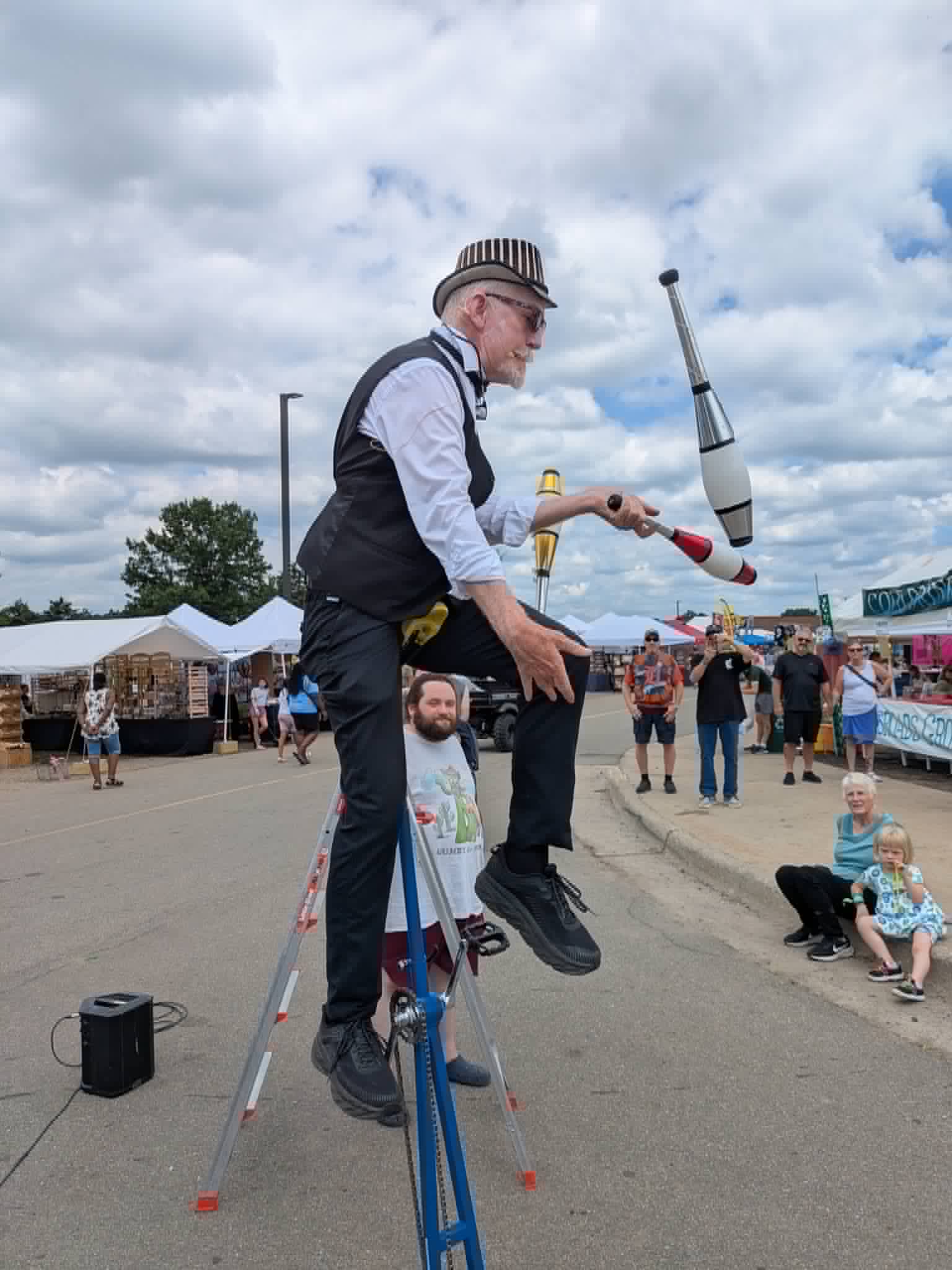 John Park The One Man Circus juggling clubs on a ladder unicycle at a Toronto street festival